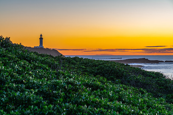 Sunrise seascape with lighthouse in the distance