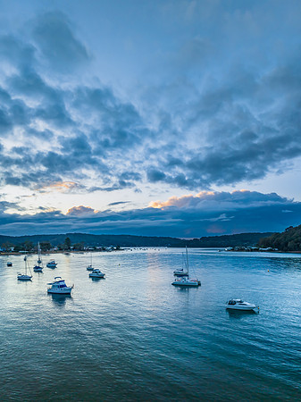 Aerial sunrise waterscape with boats and scattered rain clouds
