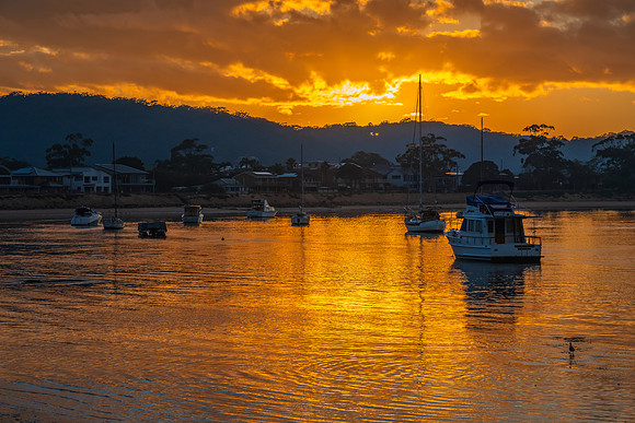 Golden sunrise waterscape with boats and cloud cover