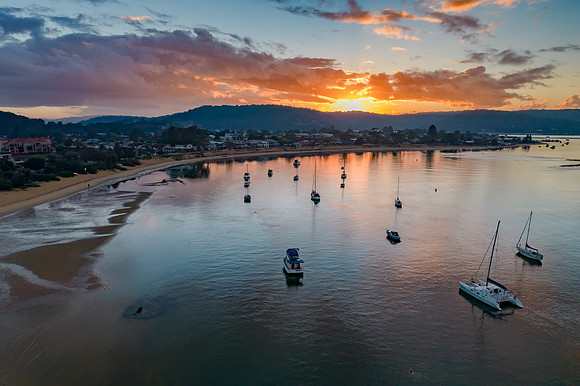 Aerial sunrise waterscape with boats and cloud cover