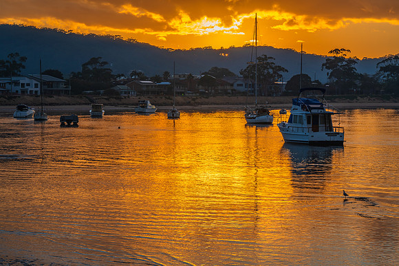 Golden sunrise waterscape with boats and cloud cover
