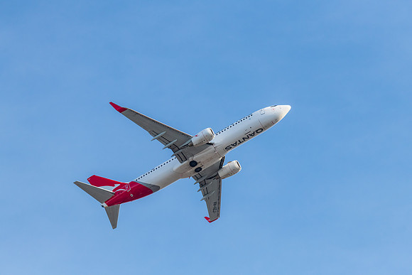 Airplane flying in blue sky with whispy white cloud