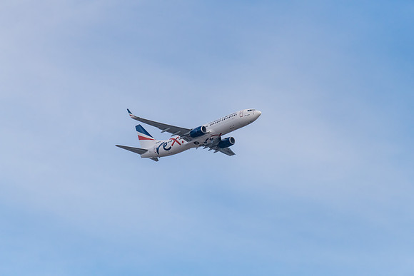 Airplane flying in blue sky with whispy white cloud