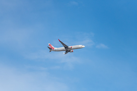 Airplane flying in blue sky with whispy white cloud