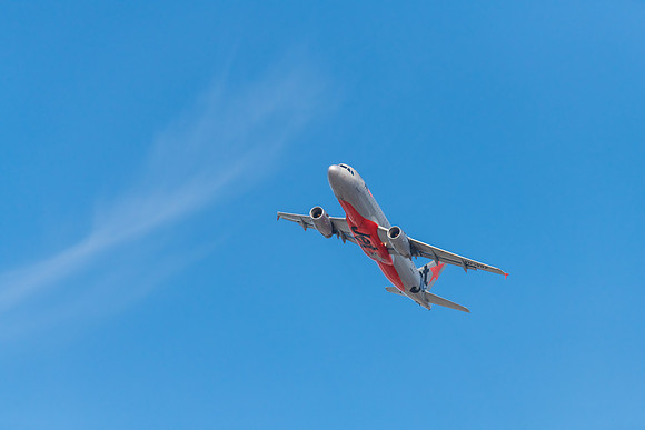 Airplane flying in blue sky with whispy white cloud