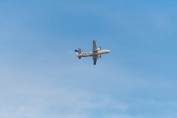Airplane flying in blue sky with whispy white cloud