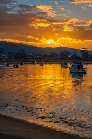 Golden sunrise waterscape with boats and cloud cover