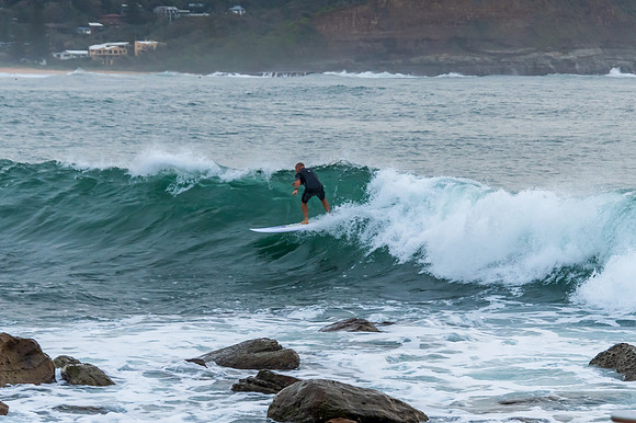Early morning seascape with surfer catching a wave