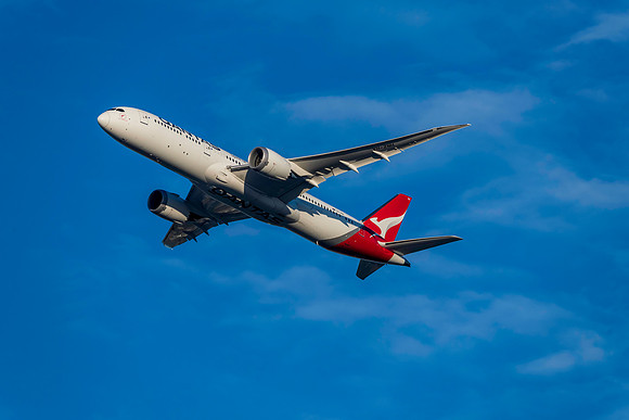 Qantas Airliner in the late afternoon blue sky with light white