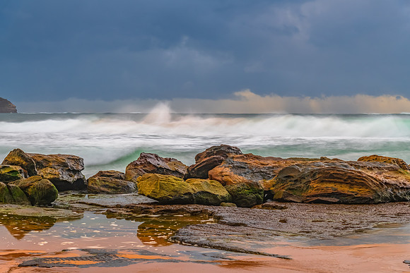 Sunrise at the seaside with rocks and rain clouds