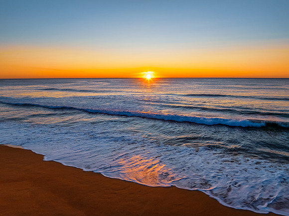 Sunrise at the seaside with clear skies and orange horizon