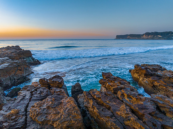 Sunrise over the ocean and rock platform with clear skies
