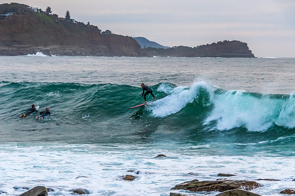 Early morning seascape with surfer catching a wave