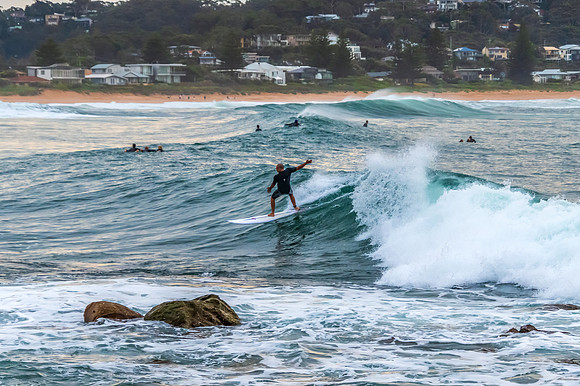 Early morning seascape with surfer catching a wave