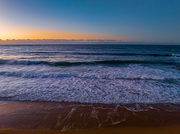 Sunrise seascape with waves and a low cloud bank