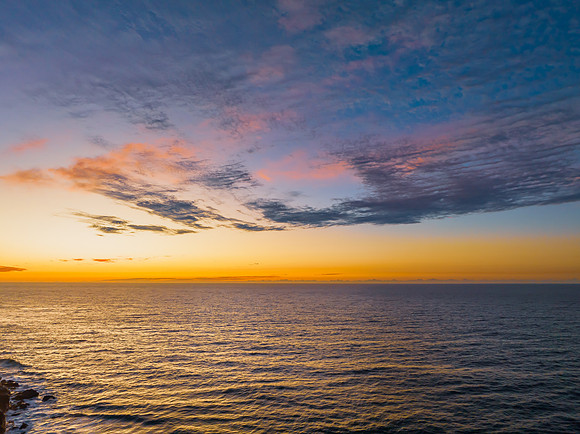Ocean sunrise with rock platform and clouds