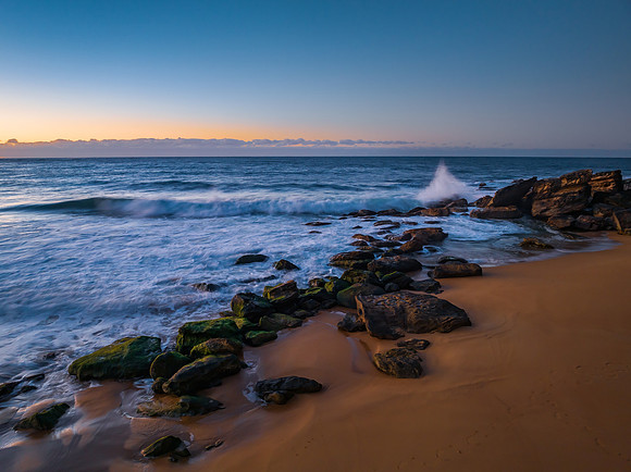 Sunrise seascape with waves and a low cloud bank
