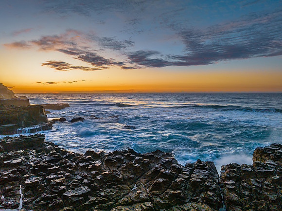 Ocean sunrise with rock platform and clouds