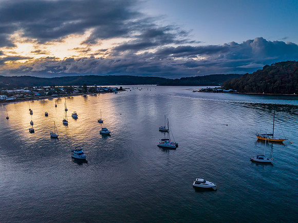 Aerial sunrise waterscape with boats and scattered rain clouds