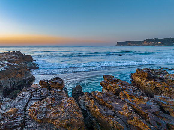 Sunrise over the ocean and rock platform with clear skies