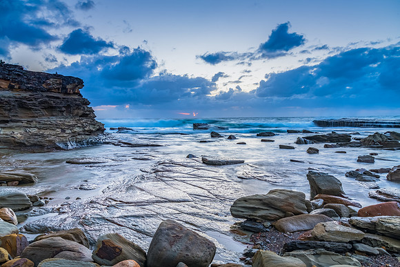 Moody sunrise seascape with clouds at the rocky inlet
