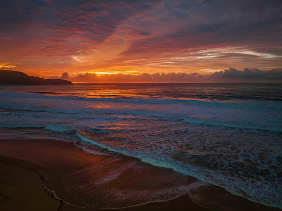Cloud covered sunrise at the seaside in pink and blue