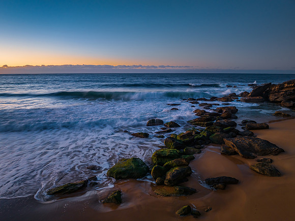 Sunrise seascape with waves and a low cloud bank