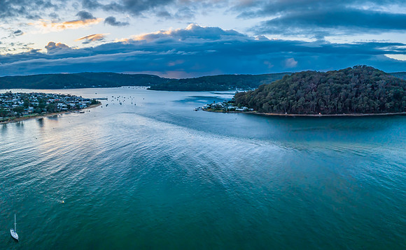 Aerial sunrise waterscape with boats and scattered rain clouds