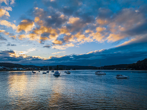 Aerial sunrise waterscape with boats and scattered rain clouds