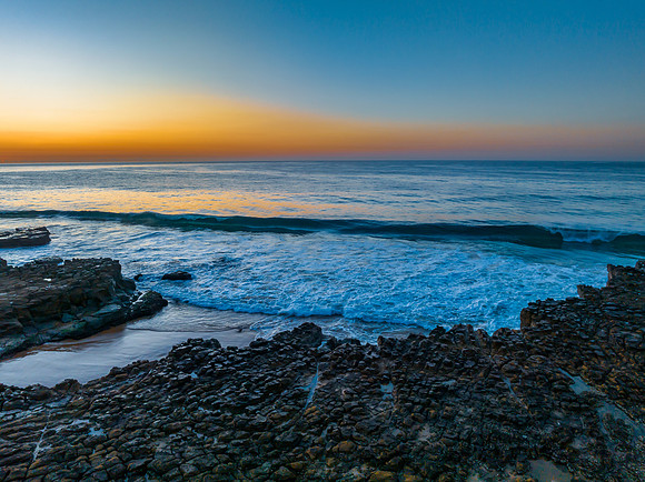 Sunrise over the ocean and rock platform with clear skies