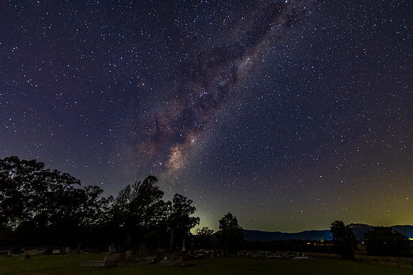 A rural cemetary with the stars and milky way sky shining bright