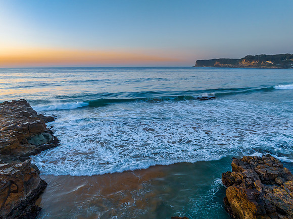 Sunrise over the ocean and rock platform with clear skies