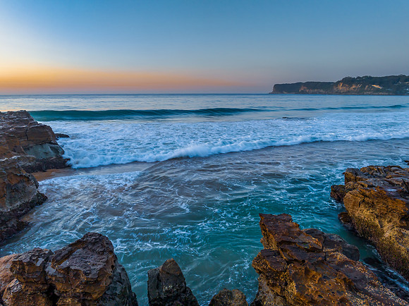 Sunrise over the ocean and rock platform with clear skies
