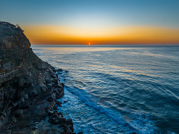 Sunrise over the ocean and rock platform with clear skies
