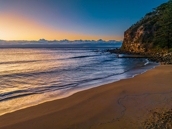 Sunrise at the seaside with low cloud bank and sea pool