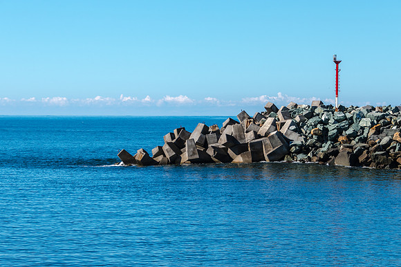 The blue river leading into the sea and rocky breakwall