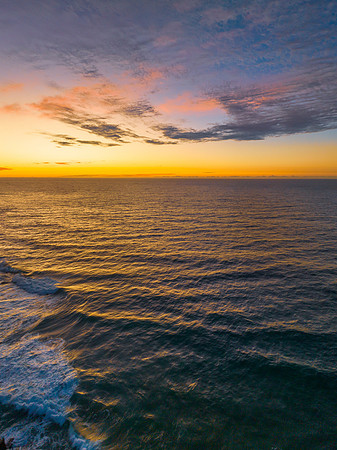 Ocean sunrise with rock platform and clouds