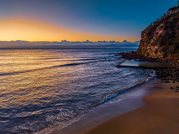 Sunrise at the seaside with low cloud bank and sea pool