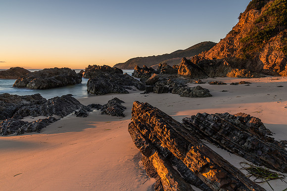 Sunrise seascape and a rocky beach softly lit by sunlight