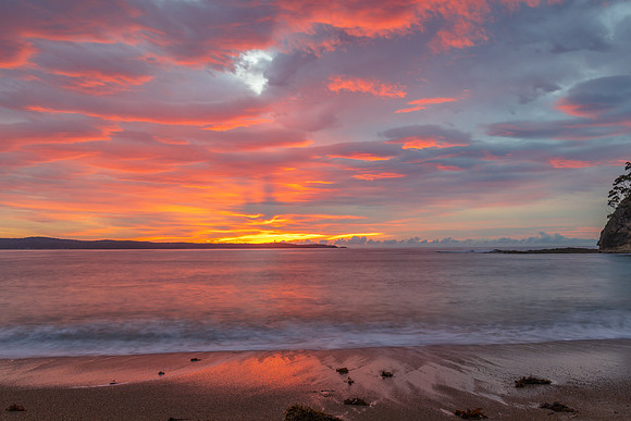 Cloud covered sunrise seascape tinged with pink
