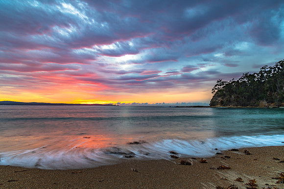 Cloud covered sunrise seascape tinged with pink