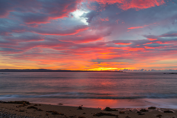 Cloud covered sunrise seascape tinged with pink