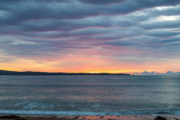 Cloud covered sunrise seascape tinged with pink