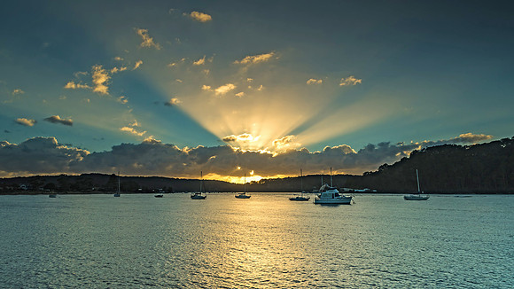 Sunrise Waterscape with Boats and Sun Rays
