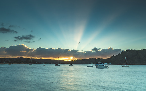 Sunrise Waterscape with Boats and Sun Rays