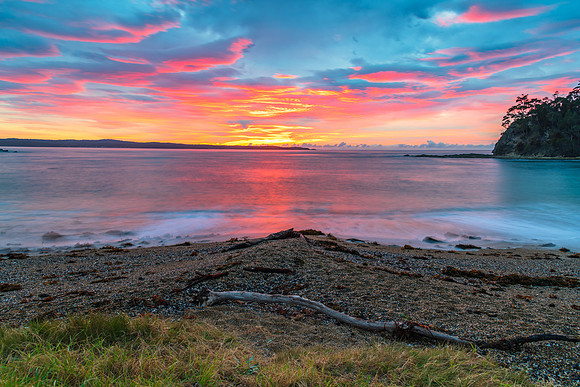 Cloud covered sunrise seascape tinged with pink