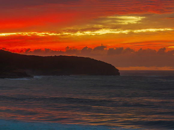 Vivid cloud covered sunrise seascape with headland