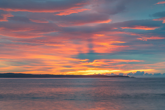Cloud covered sunrise seascape tinged with pink