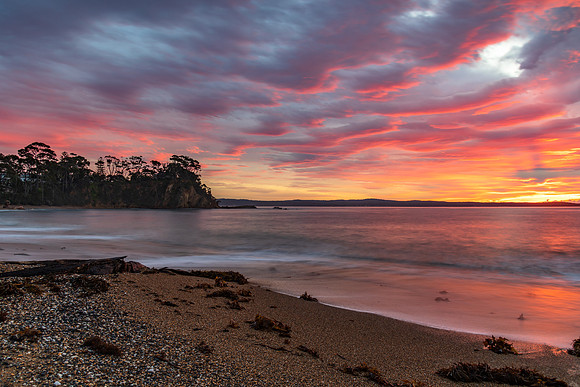 Cloud covered sunrise seascape tinged with pink