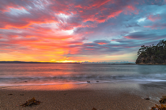 Cloud covered sunrise seascape tinged with pink